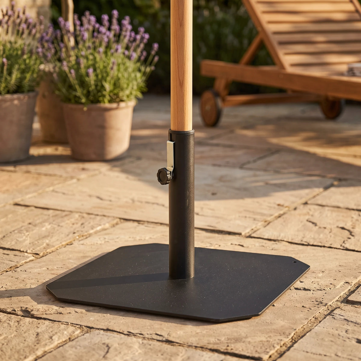 Square Parasol Base 50 x 50 cm in black iron holding a wooden parasol pole on a stone terrace